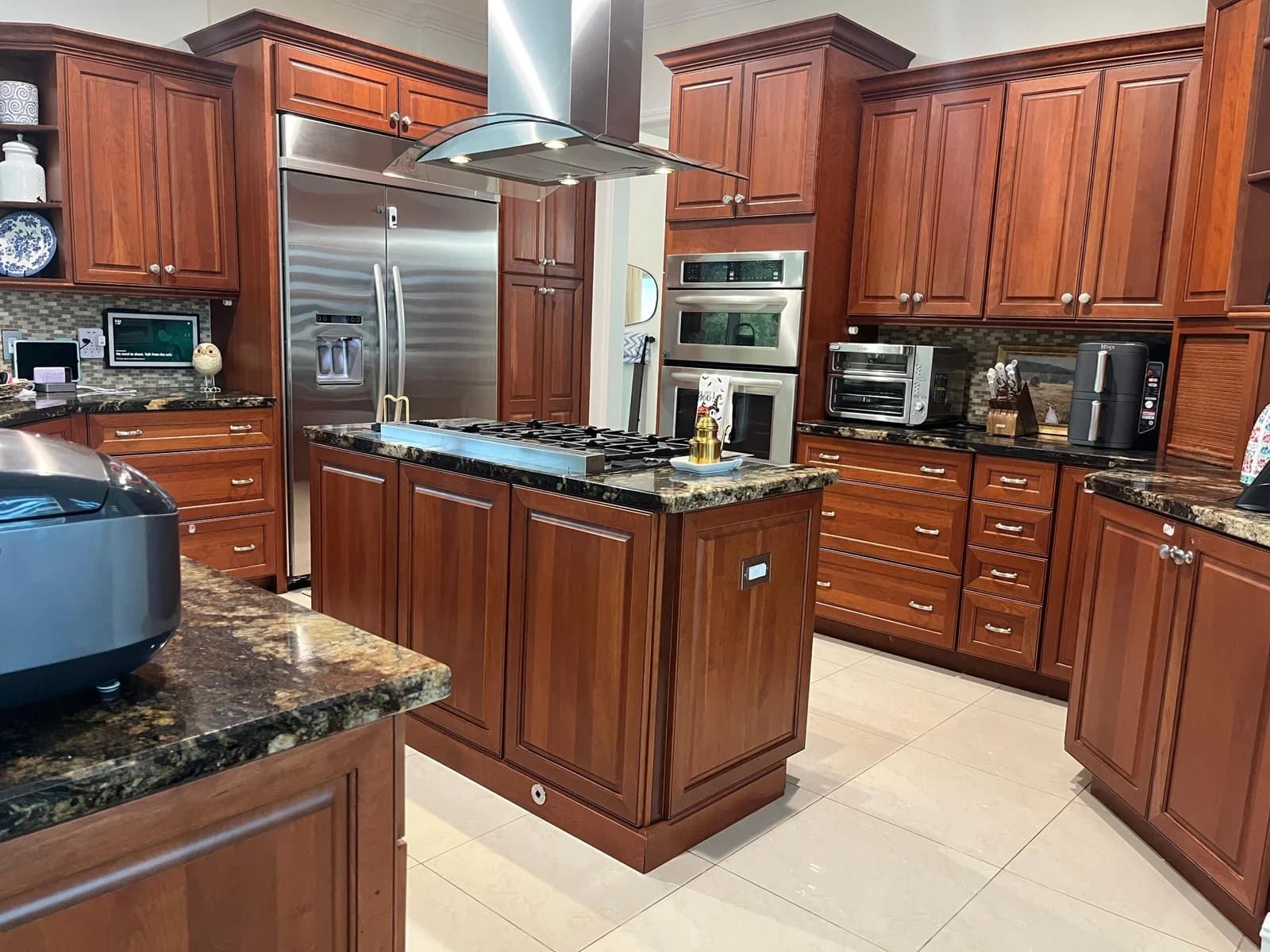 A cherry-wood kitchen with stainless appliances, cleaned and organized.