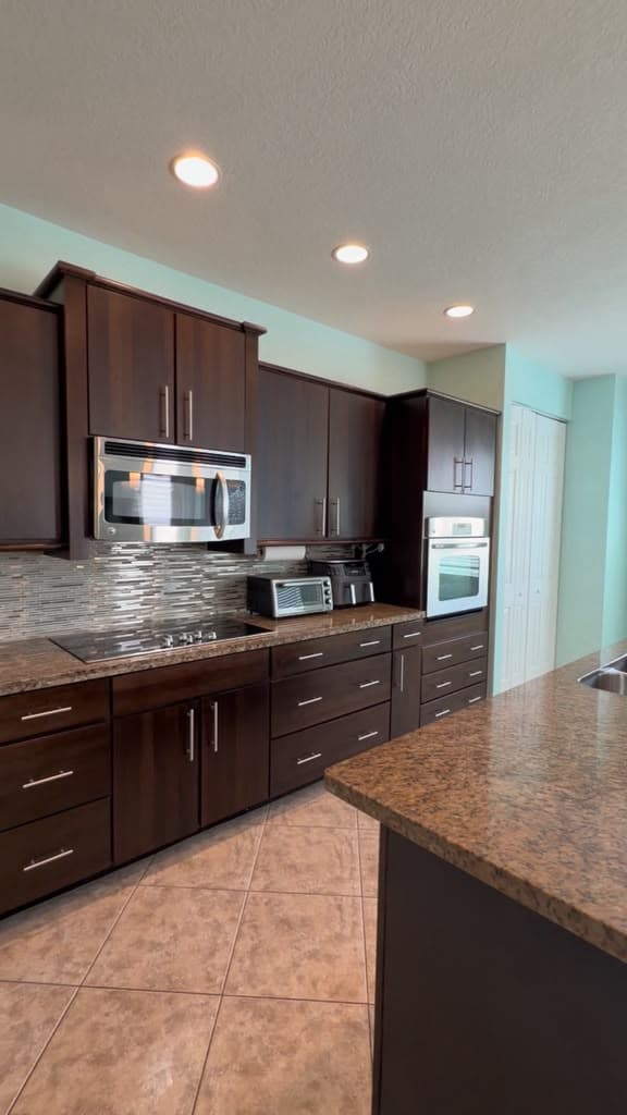 A dark-wood kitchen with stainless steel appliances and spotless countertops.