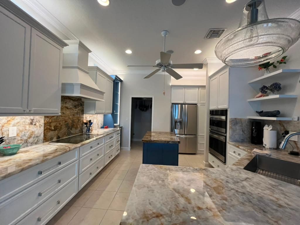 A large kitchen with granite countertops and an island, polished and spotless.