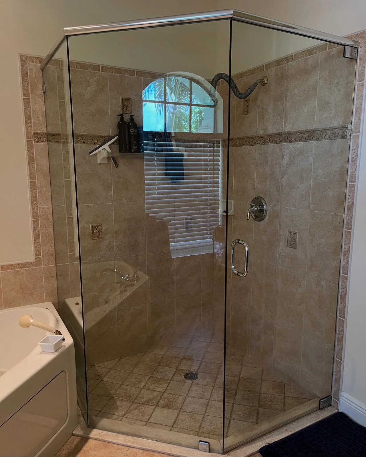 A corner glass shower with tile walls, cleaned and streak-free.